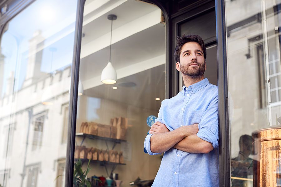Business Insurance - Portrait of Young Small Business Owner Standing Next to His Coffee Shop with His Arms Folded in the City