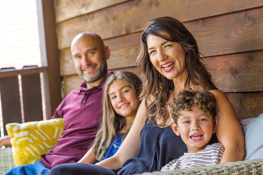 Personal Insurance - Closeup View of Cheerful Family with Two Kids Sitting on Front Porch of Their Home